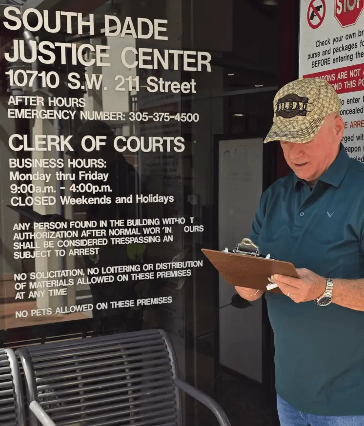Clifford Schimek reviewing a clipboard outside the South Dade Justice Center, discussing car insurance after a Florida DUI